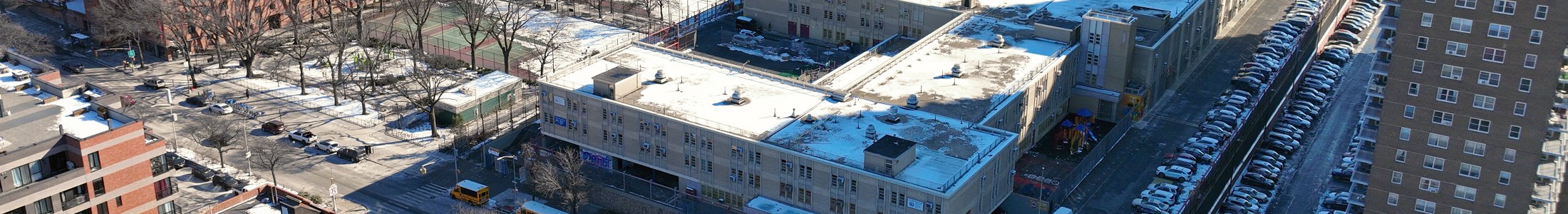 P.S. 200 seen from above: the school building, its rooftop playground and the tree-lined block of Adam Clayton Powell Jr. Boulevard in Harlem.